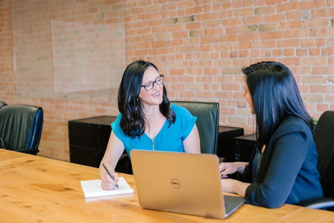 woman-in-teal-t-shirt-sitting-beside-woman-in-suit-jacket-jaovgh5aj3e